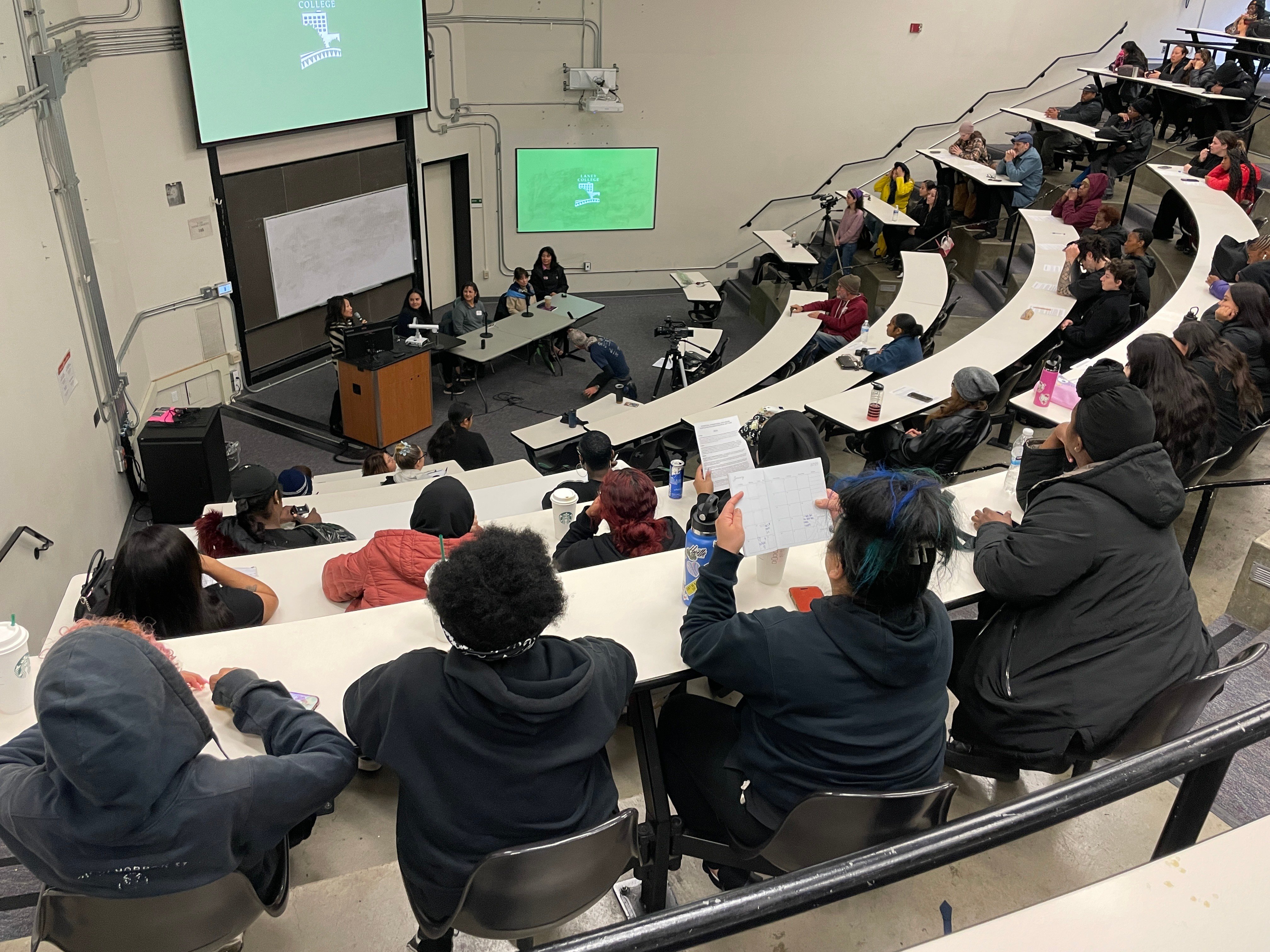 A view of the Laney College panel of Women Entrepreneurs as seen from the back of the room, showing the many students observing the discussion as well as the panelists