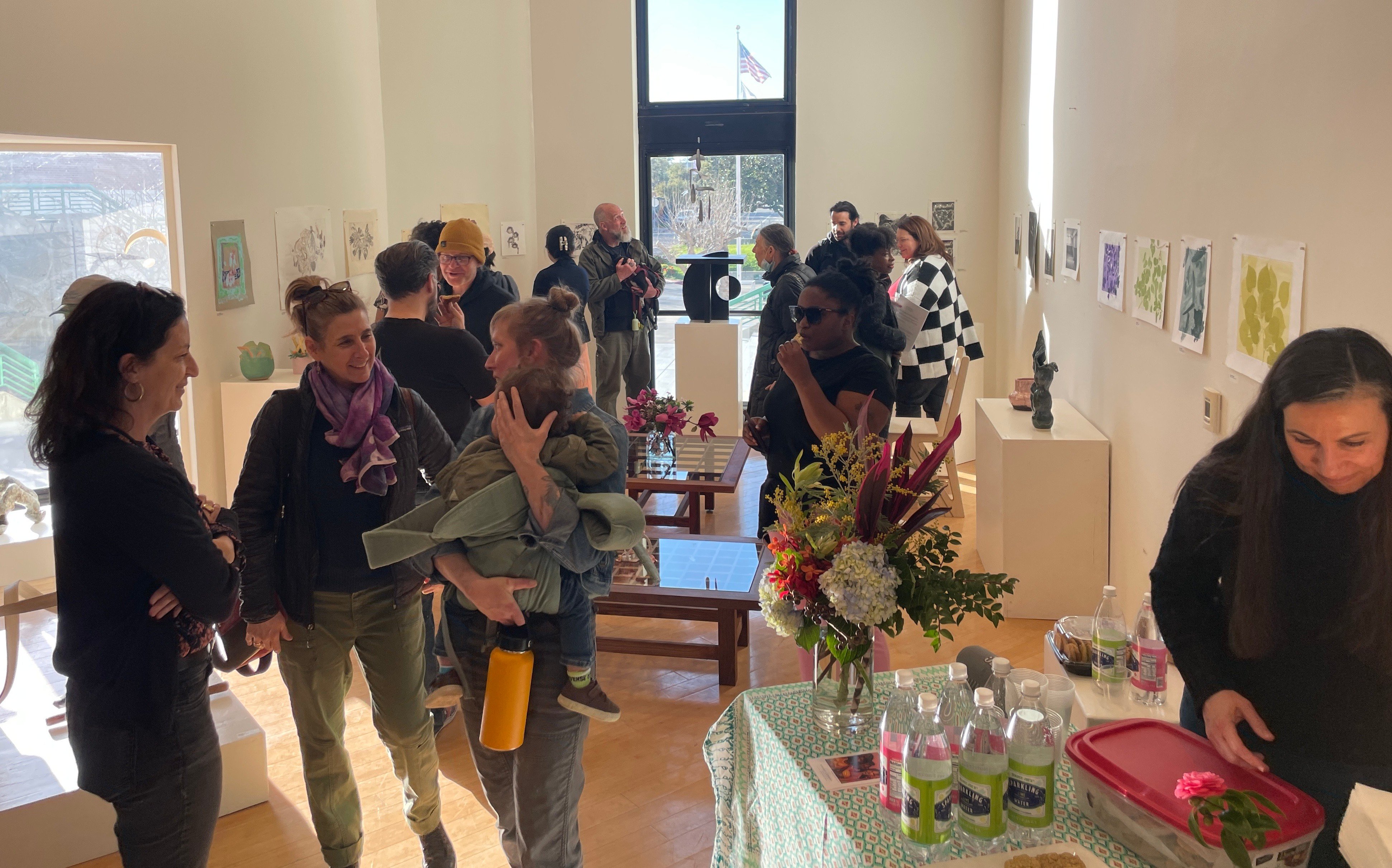 about a dozen patrons looking at artworks at the Laney College art gallery