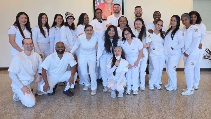 A group of Merritt College nursing students dressed all in white smile as they prepare for Graduation May 2026
