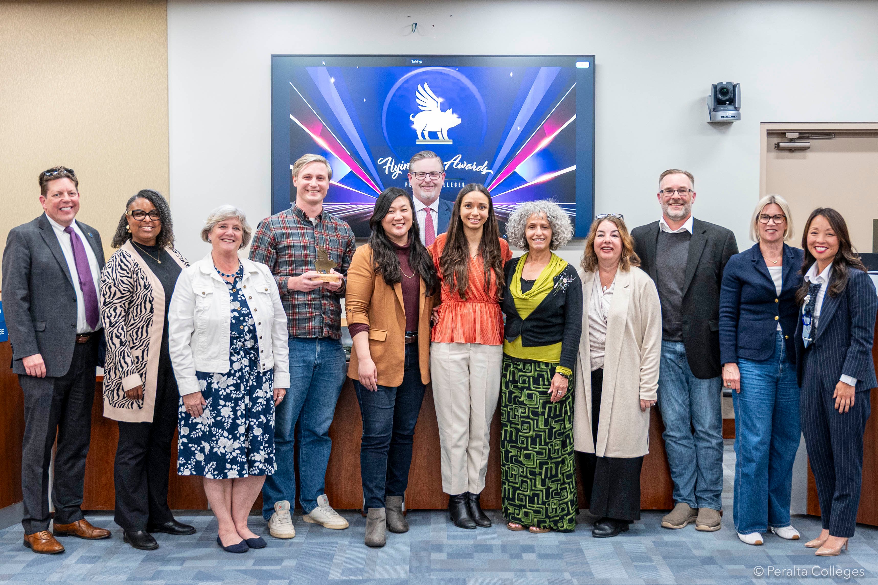 12 people standing and smiling, they are Dr. Gilkerson with the Student Success and Enrollment Management Committee (SSEMC) - Mark Johnson, Janelle Tillotson, Leslie Blackie, Tom Rizza, Helen Ku, Greg Nelson, Sabrina Manrique, Faiza Ali, Tina Vasconcellos, Matt Freeman, Lisa Cook, with Dr. Gilkerson