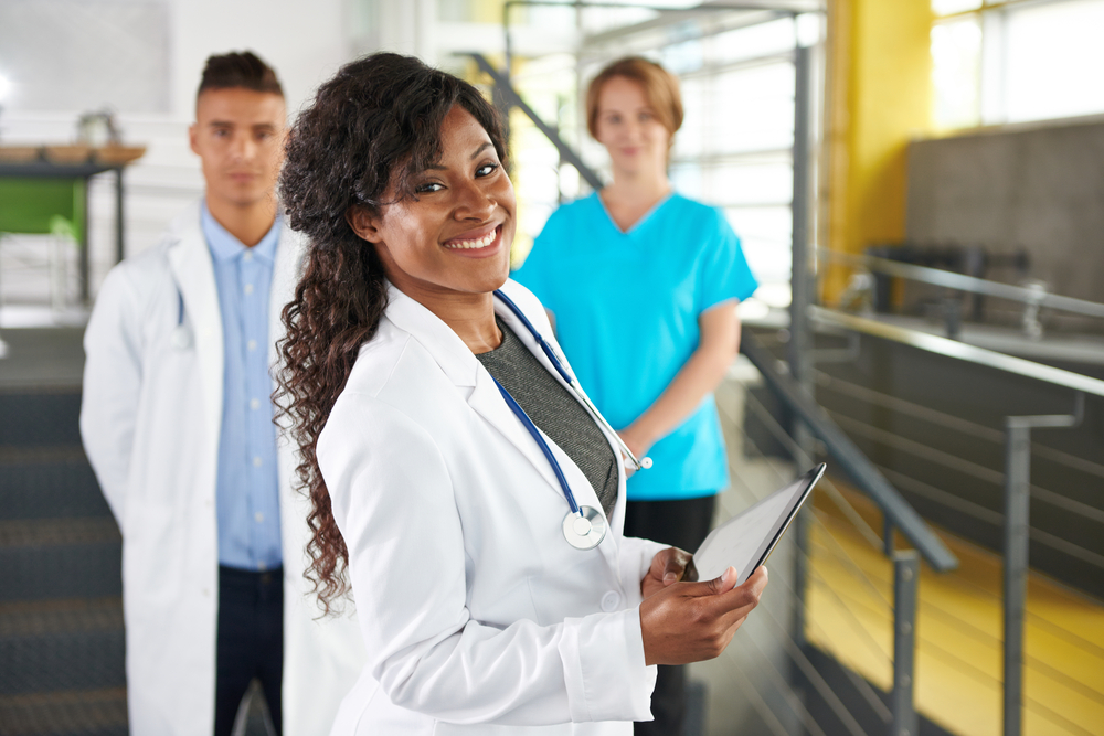 Portrait of a friendly female african american doctor and team in bright modern office