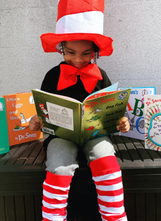 young girl smiles reading a book