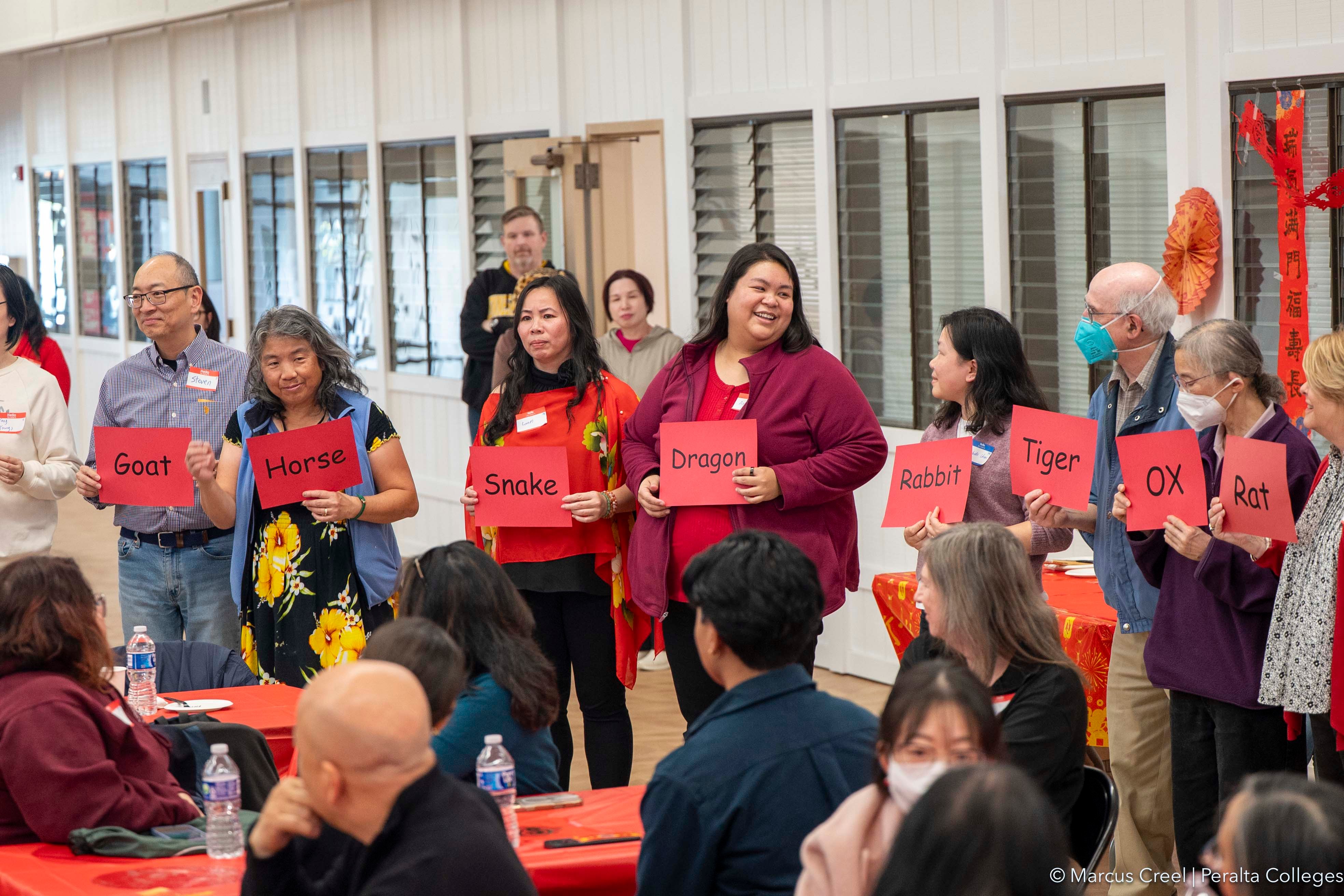 Several Peralta employees hold up signs representing symbols of the Lunar zodiac